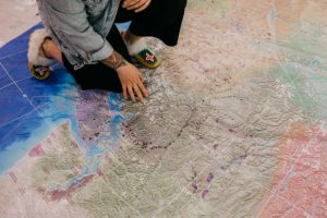 Person kneeling over the Indigenous Atlas of Canada Giant Floor Map