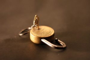 Open gold padlock with key on a neutral background