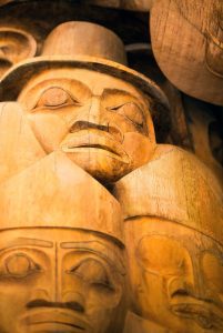 A detail of wood carved faces in the UBC reconciliation pole by Master carver 7idansuu (Edenshaw), James Hart.